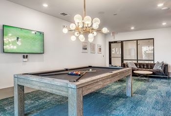 A pool table with a TV showing a game in the background.